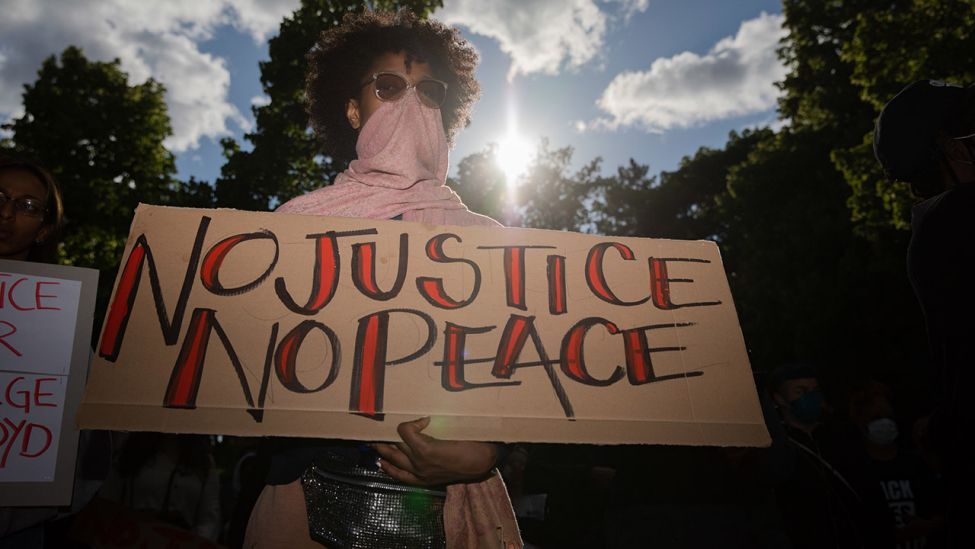 Eine Teilnehmerin hält bei einer Kundgebung vor der US-Botschaft gegen den gewaltsamen Tod des Afroamerikaners George Floyd durch einen weißen Polizisten ein Plakat mit der Aufschrift „No justice no peace“ (Ohne Gerechtigkeit kein Frieden). (Quelle: dpa/C. Soeder)