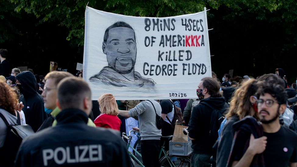 Ein Plakat mit dem Gesicht von George Floyd wird bei einer Kundgebung vor der US-Botschaft gegen den gewaltsamen Tod des Afroamerikaners durch einen weißen Polizisten in die Höhe gehalten. (Quelle: dpa/C. Soeder)