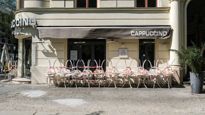 Die Tische vor dem Grand Cafe Cappuccino in der Knesebeckstraße in Charlottenburg sind hochgestellt und mit Absperrband umwickelt. (Quelle: dpa/Jens Kalaene)
