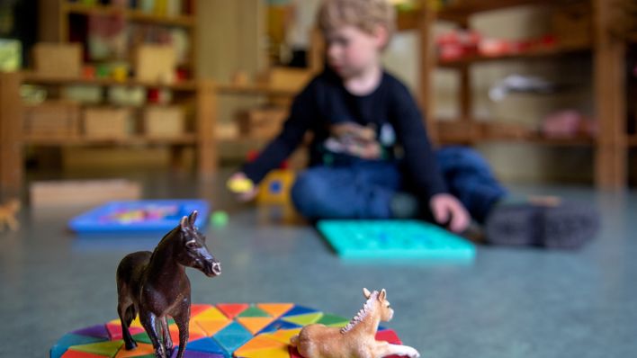 Symbolbild: Ein Junge spielt in einem Kindergarten auf dem Boden mit Plastikfiguren. (Quelle: dpa)
