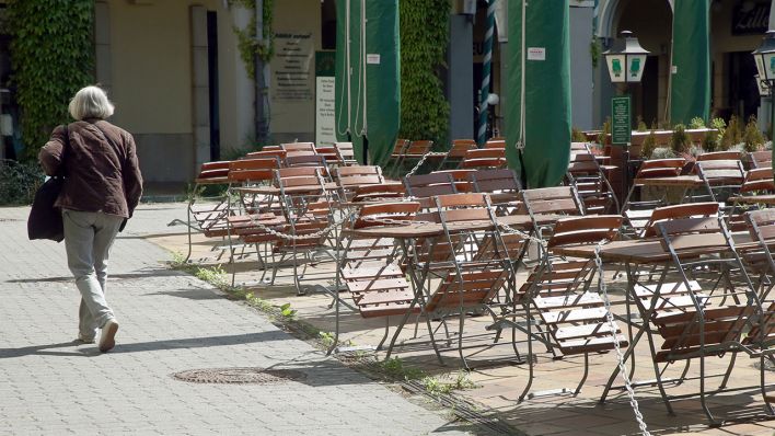 Eine Frau geht im Nikolaiviertel an leeren Tischen und Stühlen eines geschlossenen Restaurants vorbei. (Quelle: dpa/Wolfgang Kumm)