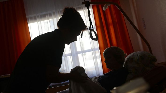 Symbolbild: Eine Frau wird in einem Seniorenpflegeheim von einer Pflegerin betreut (Quelle: dpa/Jens Kalaene)