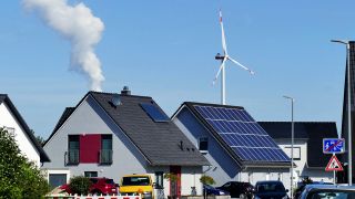 Symbolbild: Solarmodule auf Hausdächern, im Hintergrund eine Windkraftanlage und die Dampfwolke aus dem Kühlturm eines Kohlekraftwerks. (Quelle: dpa/P. Eckenroth)
