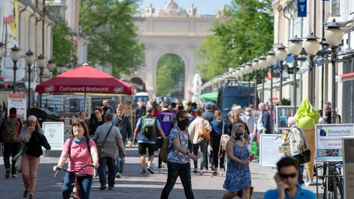 Symbolbild: Einige Passanten mit Mundschutz gehen auf der gut besuchten Einkaufsmeile Brandenburger Straße entlang. (Quelle: dpa/S. Stache)