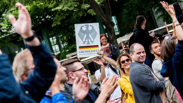 Ein Mann hält ein Grundgesetz-Plakat in Berlin-Mitte auf der Straße «Unter den Linden» bei einer Kundgebung gegen die Corona-Einschränkungen. (Quelle: dpa/Carsten Koall)