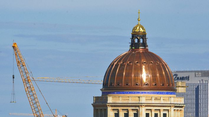 Auf der Kuppel des Humboldt Forums glänzt das goldene Kreuz in der Sonne (Quelle: Imago Images/Peter Meißner)
