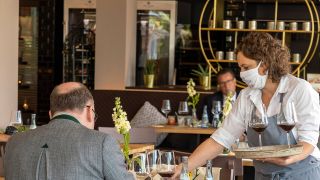 Symbolbild: Eine Kellnerin bedient einen Herren im hauseigenen Hotel-Restaurant. (Quelle: imago images/A. Hettrich)