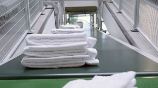 Frisch gewaschene und gefaltete Handtücher liegen auf einem Fließband (Quelle: rbb/Kowalski & Schmidt)
