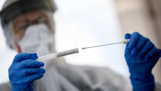 Eine Mitarbeiterin vom Gesundheitsamt in Mitte hält am 23.04.2020 ein Abstrichstäbchen in einer ambulanten Corona Test-Einrichtung in der Hand. (Quelle: dpa/Britta Pedersen)