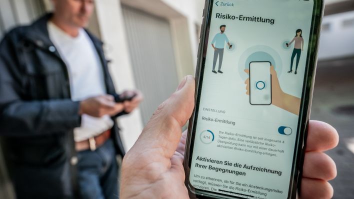 Ein Mann schaut sich die Corona-Warn-App auf seinem Smartphone an. (Quelle: dpa/Michael Kappeler)