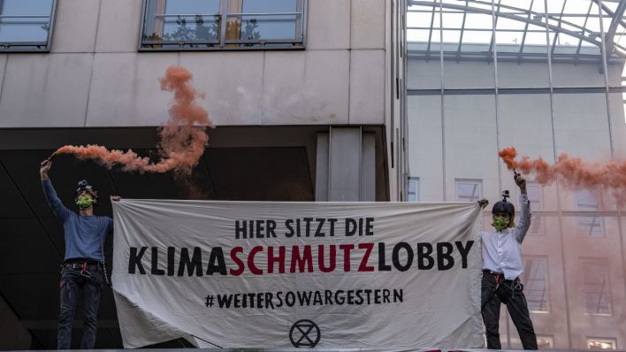 Aktivisten der Umweltschutzbewegung Extinction Rebellion (XR) stehen mit farbigen Rauchfackeln einem Transparent vor dem Haus des Bundesverbandes der Deutschen Industrie (BDI) mit der Aufschrift «Hier sitzt die Klimaschutzlobby».