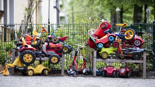 Bobby-Cars, andere Spielautos und Gefährte für Kinder liegen angeschlossen vor einer Kita in Berlin-Wilmersdorf auf einem Stapel. (Quelle: dpa/Christoph Soeder)