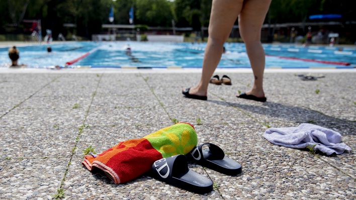Badeschlappen und Handtücher liegen im Sommerbad Humboldthain am Beckenrand. (Quelle: dpa/Christoph Soeder)
