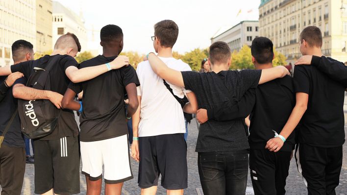 Symbolbild: Jungen aus einer Sportmannschaft mit unterschiedlichem Migrationshintergrund stehen vor dem Brandenburger Tor. (Quelle: dpa/W. Steinberg)