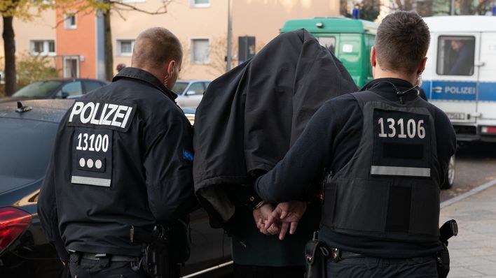 Symbolbild: Polizeibeamte führen mit Handschellen einen festgenommenen Mann ab. (Quelle: dpa/P. Zinken)