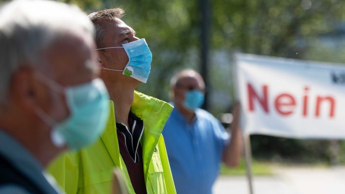 Demonstranten beteiligen sich mit einem Mundschutz an einer Demonstration (Quelle: dpa/Bernd Thissen)