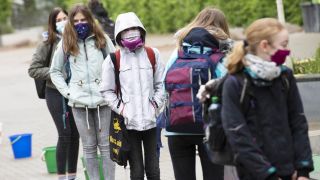 Mit Abstand und Gesuchtsmasken warten Schülerinnen und Schüler der Comenius Grundschule auf ein Zeichen einer Lehrerin. (Quelle: dpa/Paul Zinken)