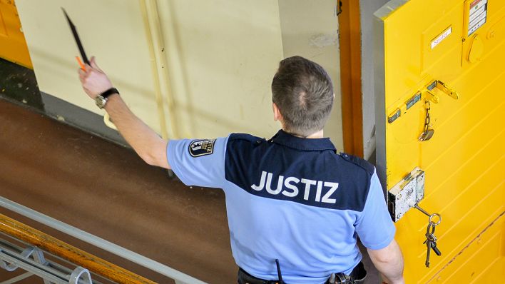 Symbolbild: Ein Justizvollzugsbeamter steht in Berlin in der Justizvollzugsanstalt Moabit vor einer geöffneten Zellentür. (Quelle: dpa/Tirl)