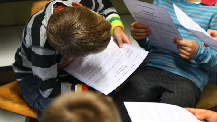 Schüler sitzen beisammen und lesen ihre Zeugnisse. Quelle: Karl-Josef Hildenbrand/dpa