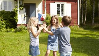 Symbolbild - Drei Kinder spielen vor einem Ferienhaus in Schweden (Bild: imago images/Westend61)
