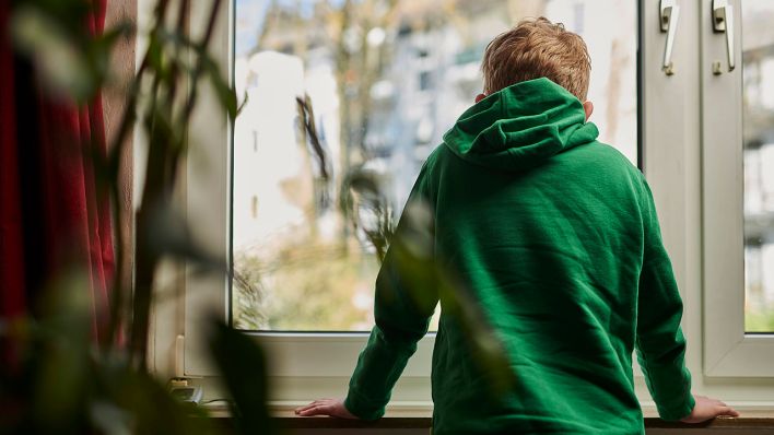 Symbolbild - Ein Junge steht am Fenster in einer Wohnung (Bild: imago images/Markus Mielek)