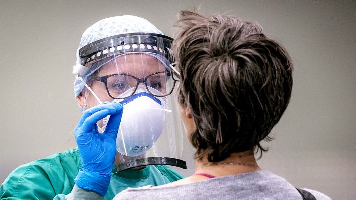 THEMENBILD - Mitarbeiter des Roten Kreuzes nimmt mit einem Staebchen einen Abstrich bei Personen mit Erkrankungsverdacht (Quelle: imago-images)