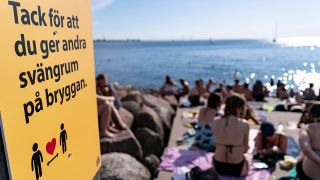 Eine Infotafel weist an einem Strand in Schweden darauf hin, Abstand zu halten (Quelle: imago images/TT)