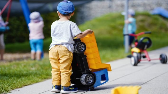 Ein Kind spielt in einer Kindertagesstätte mit einem Plastikfahrzeug.