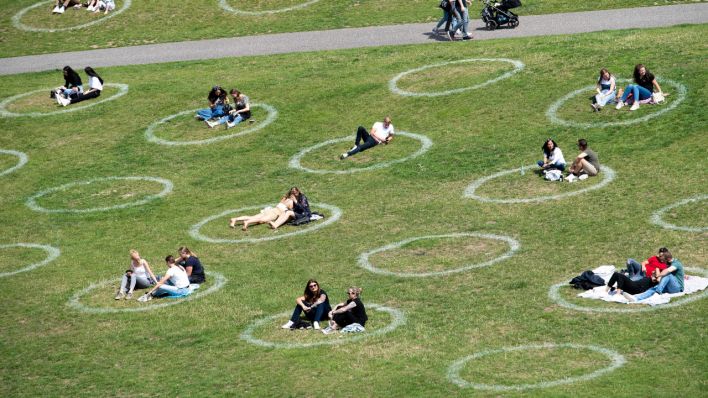 Symbolbild: Menschen sitzen auf einer Wiese in aufgemalten Kreisen. Die Kreise sollen die Einhaltung des Mindestabstandes während der Corona-Pandemie gewährleisten. (Quelle: dpa/Marius Becker)