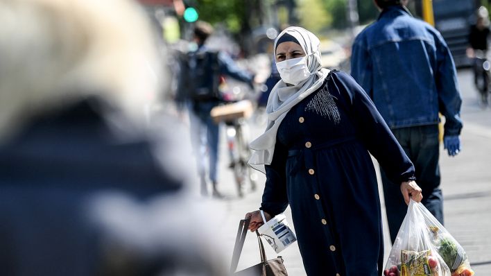 Eine Frau trägt ihre Einkäufe mit einem Nasen-Mund-Schutz (Bild: dpa/Britta Pedersen)