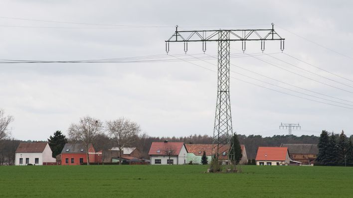 Ein Freileitungsmast steht auf einem Feld neben einem Dorf in Brandenburg (Quelle: DPA/Soeren Stache)