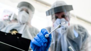 Berlin: Mitarbeiter vom Gesundheitsamt in Mitte halten ein Abstrichstäbchen (Quelle: dpa/Pedersen)
