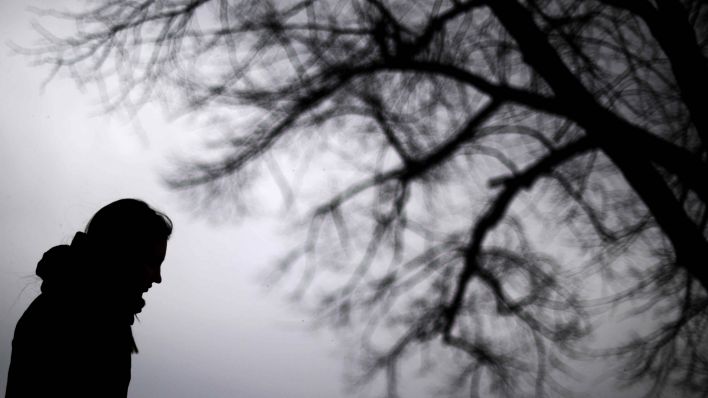 Symbolbild: Die Silhouette einer Frau vor einem winterlichen, weit verzweigtem Baum. (Quelle: dpa/J. Stratenschulte)