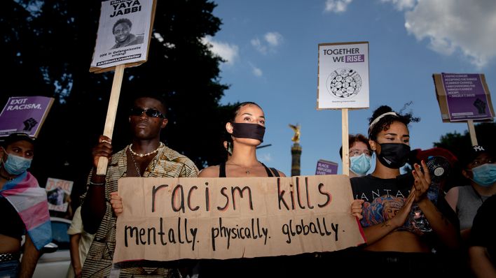Teilnehmer einer Demonstration in Berlin gegen Rassismus und Polizeigewalt halten Schilder in den Händen. (Quelle: dpa/Christoph Soeder)