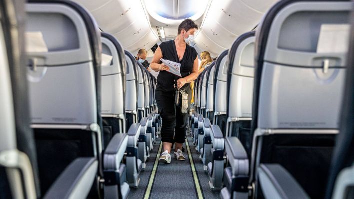 Eine Frau sucht ihren Platz in einem Flugzeug (Quelle: Imago Images/Jeffrey Groeneweg)