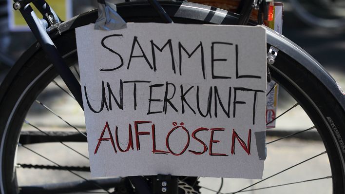 Symbolbild: Ein Schild mit der Aufschrift Sammelunterkunft Auflösen hängt an einem Fahrrad während einer Fahrradsternfahrt für die Auflösung von Sammelunterkünften für Geflüchtete, Potsdam. (Quelle: imago images/M. Müller)