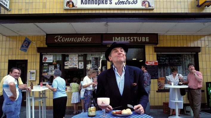 Mehr Berlin geht kaum: Schauspieler Harald Juhnke isst bei Konnopke eine Currywurst (Quelle: imago images/Gueffroy).