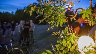 Eine kleine Diskokugel dreht sich im Volkspark Hasenheide in einem Baum, im Hintergrund stehen Menschen auf einer Wiese. (Bild: dpa/Christoph Söder)