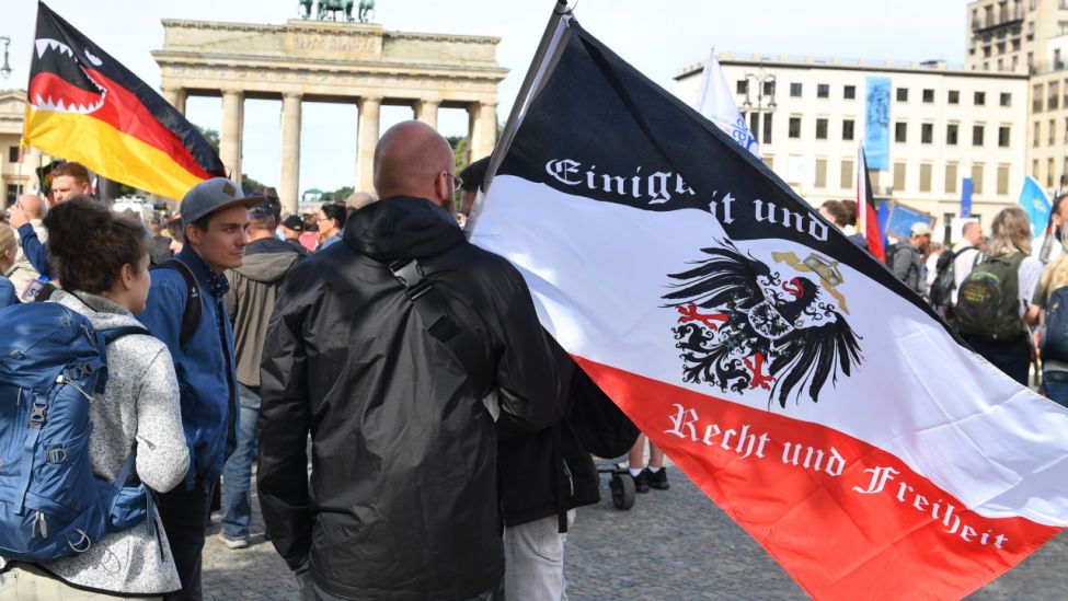 Ein Teilnehmer hält vor einer Demonstration gegen die Corona-Maßnahmen eine Reichsflagge vor dem Brandenburger Tor. (Quelle: dpa/Bernd Von Jutrczenka=