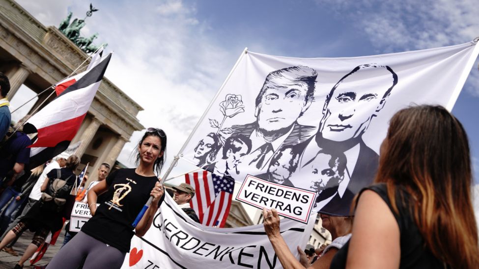 Teilnehmer sammeln sich am Brandenburger Tor zu einer Demonstration gegen die Corona-Maßnahmen und halten ein Banner mit dem Bild von US Präsident Trump und dem russischen Präsidenten Putin. (Quelle: dpa/Kay Nietfeld)