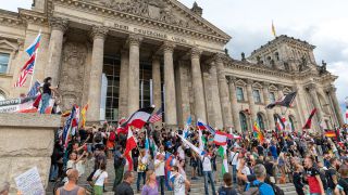 Teilnehmer einer Kundgebung gegen die Corona-Maßnahmen stehen auf den Stufen zum Reichstagsgebäude, zahlreiche Reichsflaggen sind zu sehen. (Quelle: Achille Abboud/dpa)