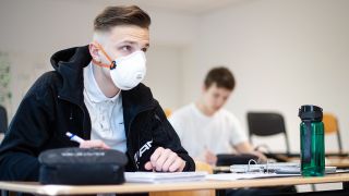 Ein Schüler sitzt mit Schutzmaske in einem Unterrichtsraum (Bild: dpa/Jonas Güttler)