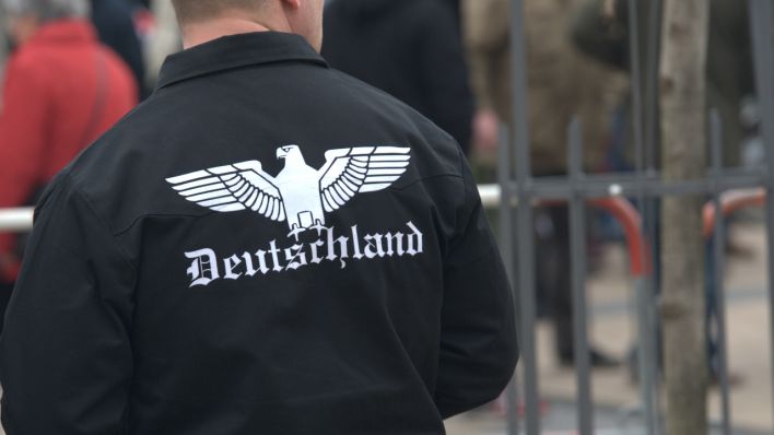 "Deutschland" steht unter einem stilisierten Reichsadler auf der Jacke eines Mannes (Quelle: DPA/Paul Zinken)