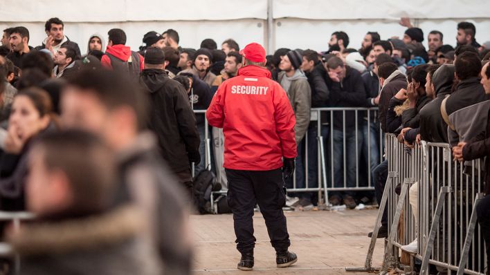 Archivbild: Flüchtlinge stehen am 26.10.2015 vor dem Landesamt für Gesundheit und Soziales (LaGeSo) in Berlin, während Mitarbeiter einer Sicherheitsfirma die Warteschlangen organisieren. (Quelle: dpa/M. Kappeler)