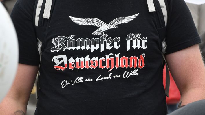 "Kämpfer für Deutschland" steht auf dem T-Shirt eines Teilnehmers an einer Demonstration von rechten Organisationen und Gruppierungen. Quelle: dpa/Paul Zinken