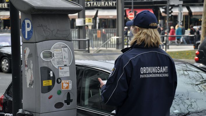 Archivbild: Eine Mitarbeiterin des Berliner Ordnungsamtes verteilt neben einem Parkautomaten Knöllchen. (Quelle: dpa/S. Steinach)
