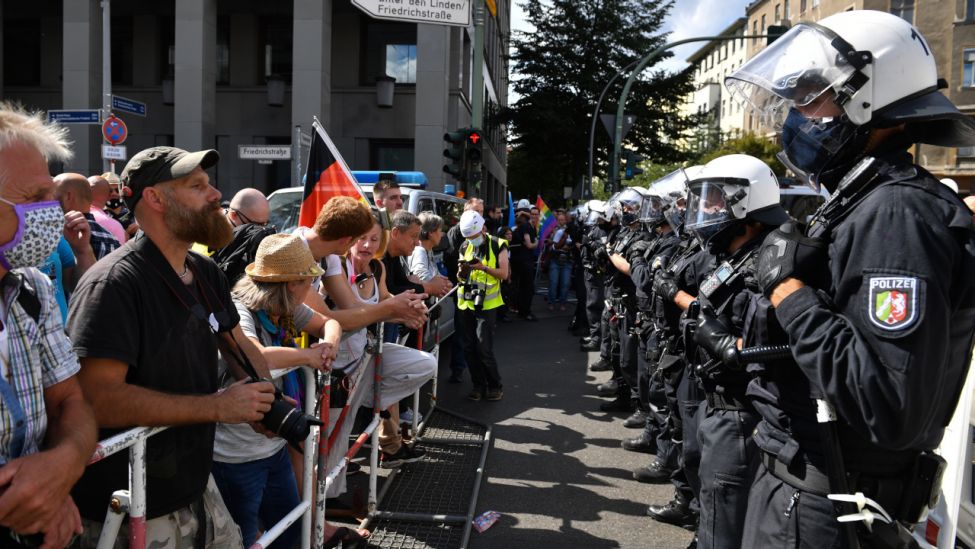 Eine Polizeikette steht an Absperrgittern den Teilnehmern gegenüber bei einer Demonstration gegen die Corona-Maßnahmen. (Quelle: dpa/Bernd Von Jutrczenka)