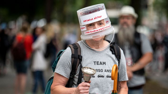 Ein Demonstrant der Querdenken-Initiative läuft mit einem beschrifteten Plastikeimer über dem Kopf durch Berlin (Bild: dpa/Fabian Sommer)