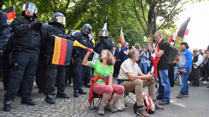 29.08.2020, Berlin: Die Teilnehmerin einer Demonstration gegen die Corona-Maßnahmen bläst in eine Vuvuzela vor einer Polizeikette (Quelle: Bernd Von Jutrczenka/dpa)