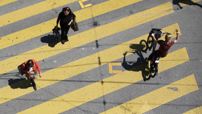 Fußgänger und eine Radfahrerin überqueren einen Zebrastreifen (Quelle: dpa/Peter Klaunzer)